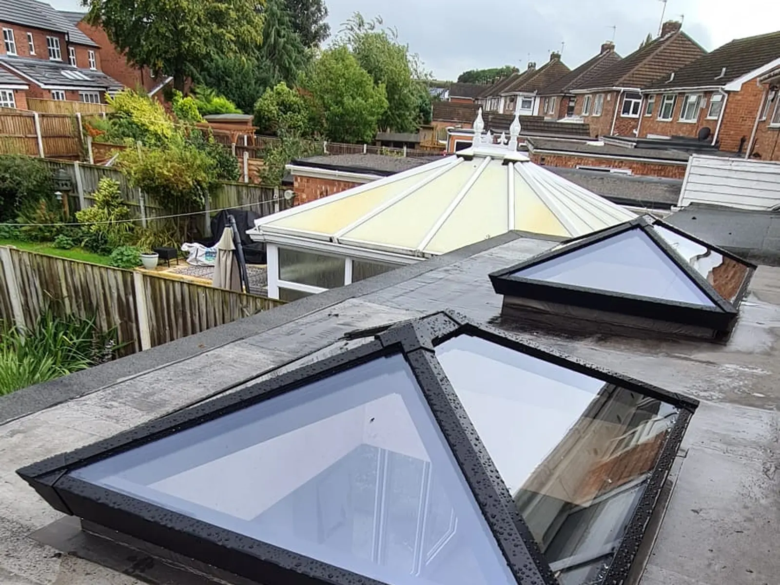 Two black framed glass roof lanterns installed on a flat felt roof