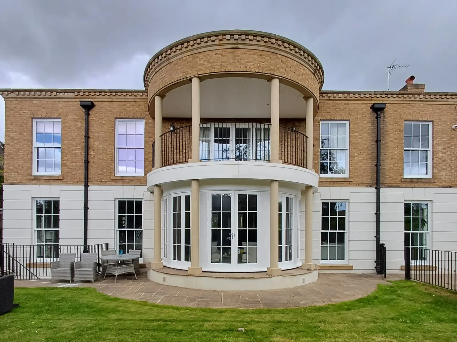 White sash windows and curved white French doors fitted to a large brick and render house