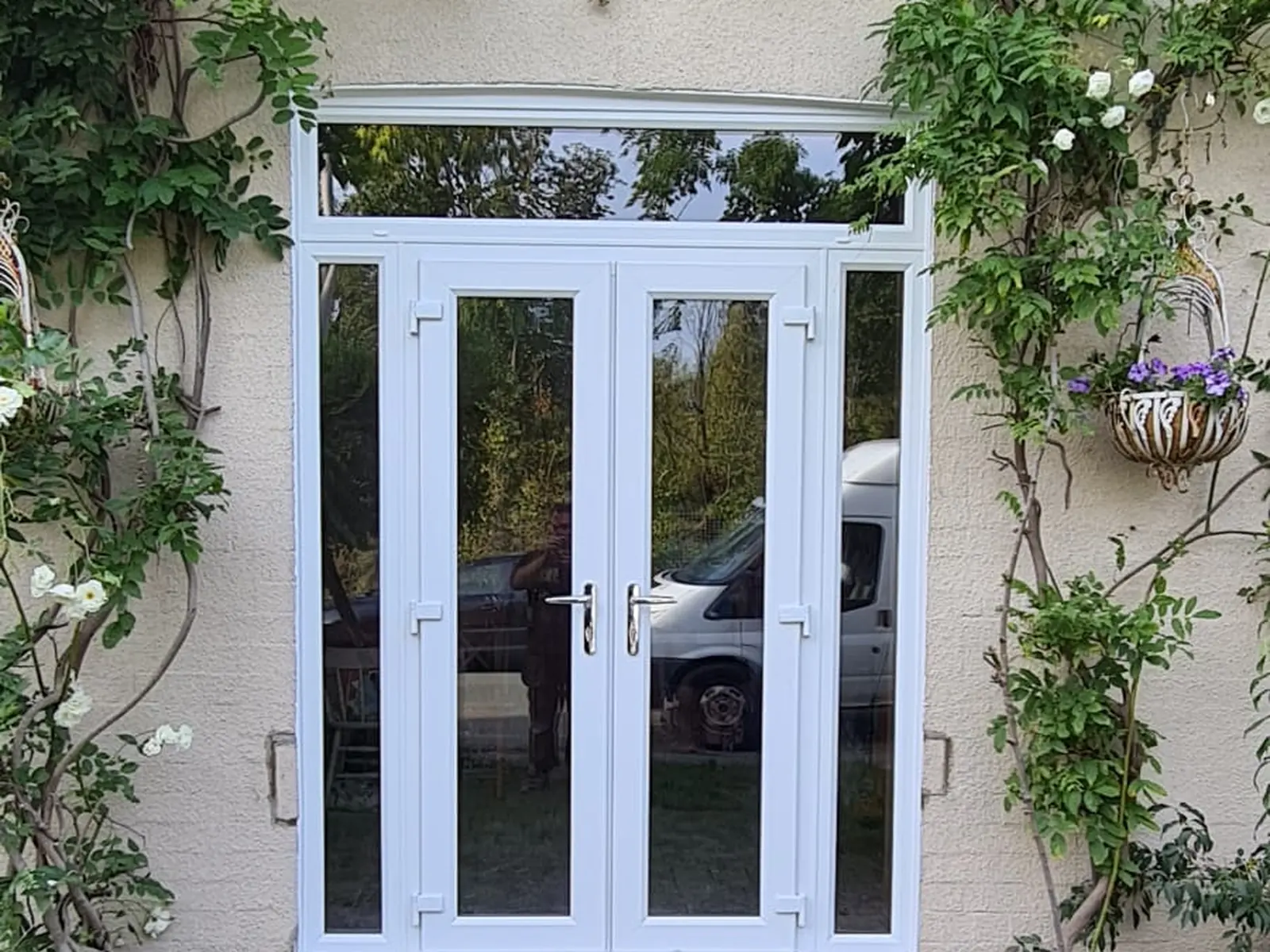 White uPVC French doors with a glazed top light fitted to a rendered house wall