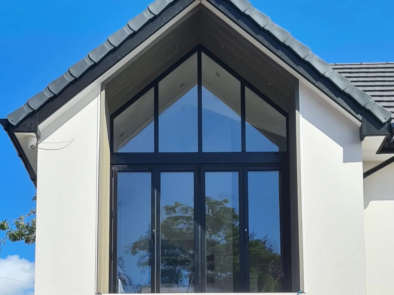 Anthracite apex gable window above dark framed patio doors on a white rendered house