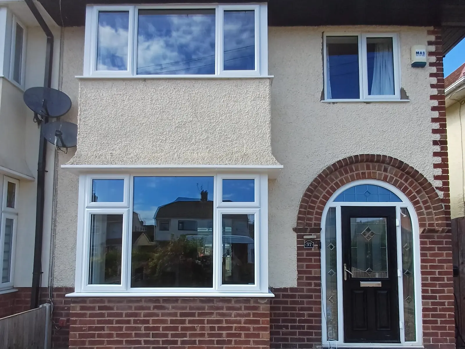 White uPVC casement windows and a black composite front door on a rendered semi-detached house